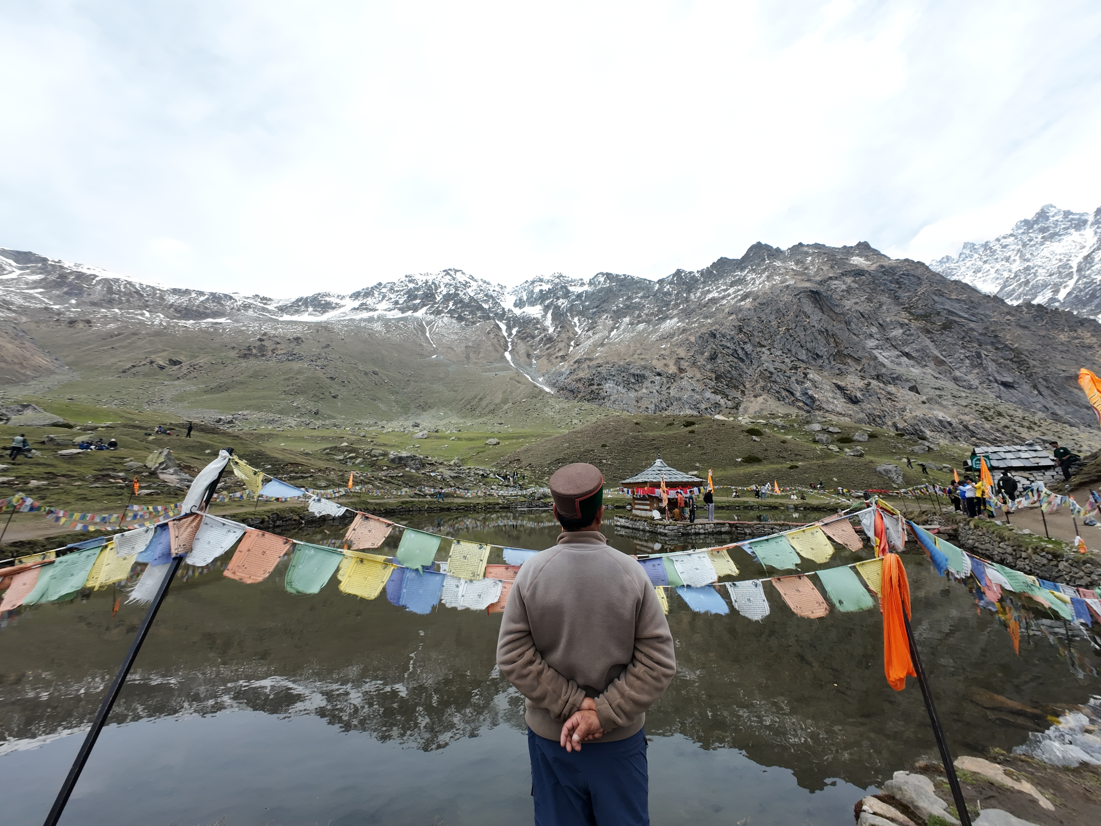 Devotee in traditional Kinnauri cap looking out over the Yulla Kanda sacred lake and temple