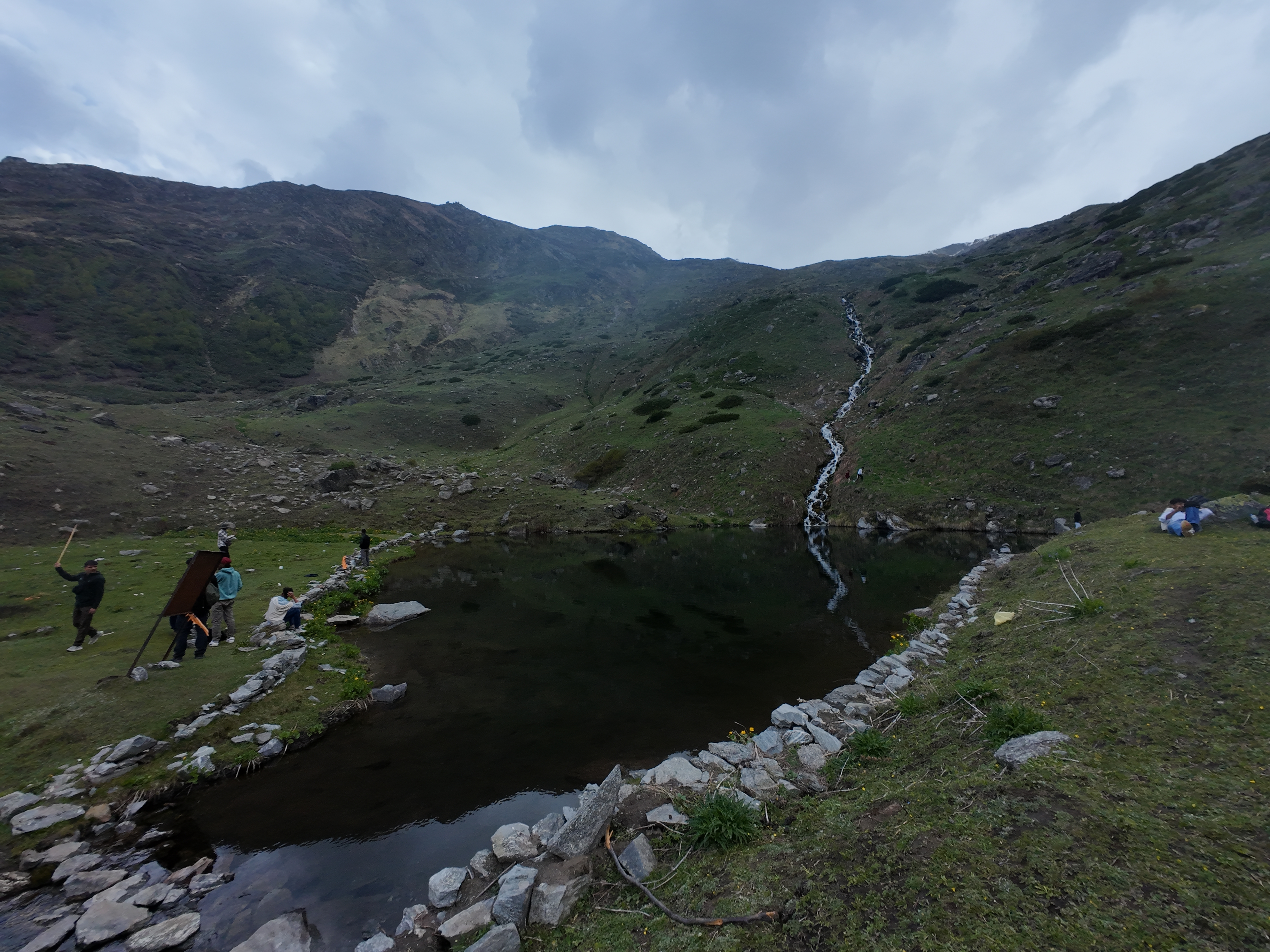 The sacred Yulla Kanda lake lined with stone embankments and a waterfall flowing in
