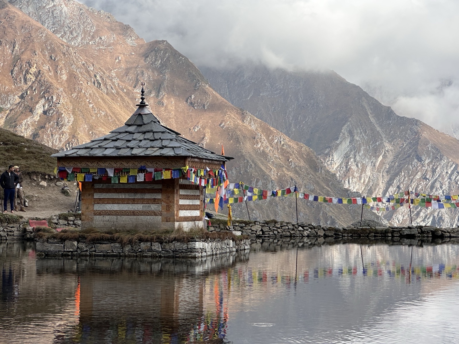 Yulla Kanda Krishna temple reflected in the sacred lake with colourful prayer flags and Kinnaur peaks